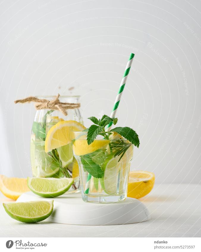 Limonade in einem transparenten Glas mit Zitrone, Limette, Rosmarinzweigen und Minzblättern auf weißem Hintergrund Kalk trinken Cocktail Erfrischung Frucht Eis