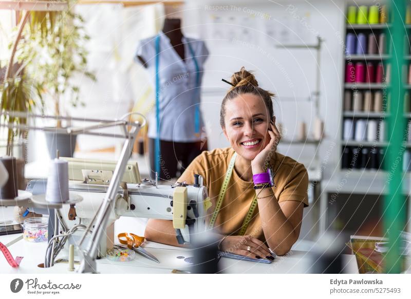 Junge Modedesignerin an ihrem Arbeitsplatz Handwerk Schneidern Herstellung handgefertigt Näherin Kleinunternehmen Nähmaschine Werkstatt Gewebe Hobby Nähen