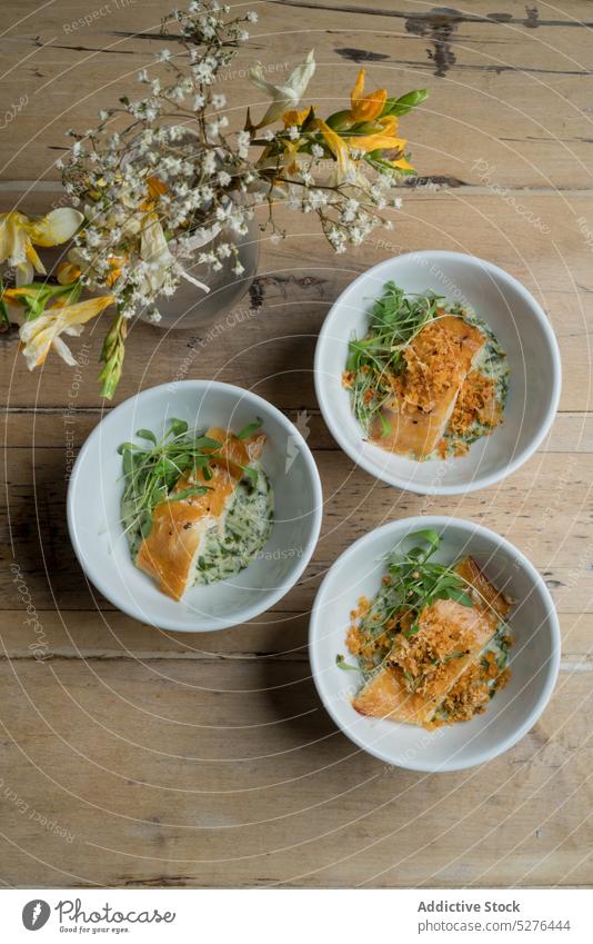 Schalen mit Fischen in der Nähe der Vase Speise Lebensmittel Mahlzeit Schalen & Schüsseln Portion Blumenstrauß Blütezeit frisch dienen Saucen appetitlich Glas