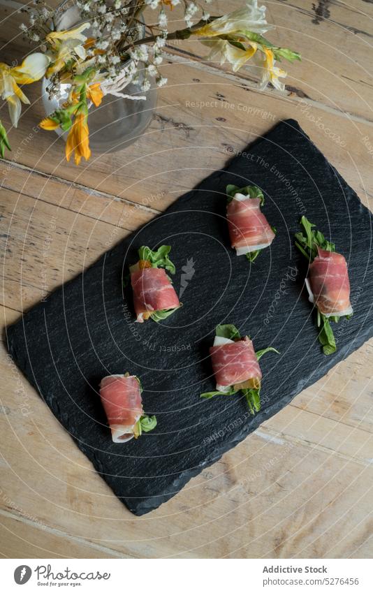 Frische Vorspeise auf schwarzem Brett neben Blumenstrauß Lebensmittel Amuse-Gueule Thunfisch rollen dienen Fisch Küche Blüte Vase Holzplatte Blütezeit Haufen