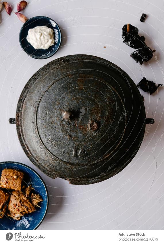 Gusseiserner Kessel auf weißem Tisch mit Zutaten Gußeisen Speise Pfanne Lebensmittel spanische Küche Schalen & Schüsseln lecker Tomate selbstgemacht Mahlzeit