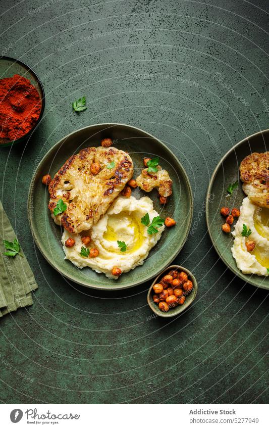 Leckeres veganes Gericht, dekoriert mit frischer Petersilie Veganer Speise Blumenkohl Braten Kartoffel gestampft Kichererbsen Gewürz dienen Teller Vegetarier