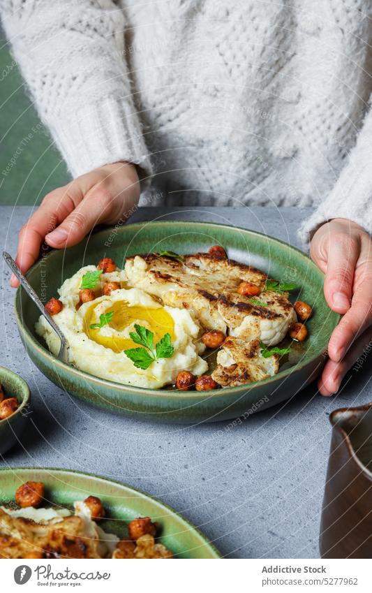 Frau mit Teller mit leckerem vegetarischem Gericht Vegetarier Speise Blumenkohl Braten Kartoffel gestampft Kichererbsen Petersilie Veganer Mahlzeit Lebensmittel