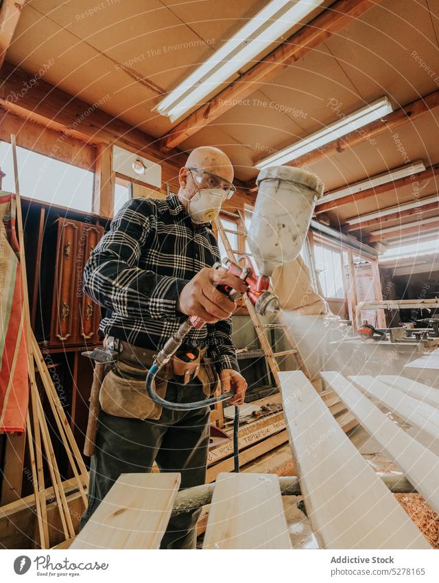 Schreiner bei der Arbeit mit einem Farbspritzgerät in der Werkstatt Mann Firnis Zimmerer Holzplatte Tischlerin Farbe Mundschutz Tischlerarbeit polnisch