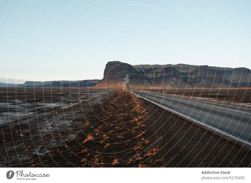 Landstraße in der Nähe von Bergen bei Sonnenuntergang Straße Berge u. Gebirge Tal Kamm Landschaft Wolkenloser Himmel malerisch Hochland Abend Island Formation