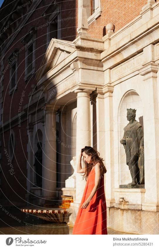 Junge Frau in rotem Kleid in der Nähe eines Brunnens. Weiblicher Tourist posiert für Fotoshooting. Mode und Stil. rotes Kleid Tourismus reisen im Freien jung