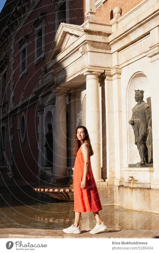 Junge Frau in rotem Kleid in der Nähe eines Brunnens. Weiblicher Tourist posiert für Fotoshooting. Mode und Stil. rotes Kleid Tourismus reisen im Freien jung