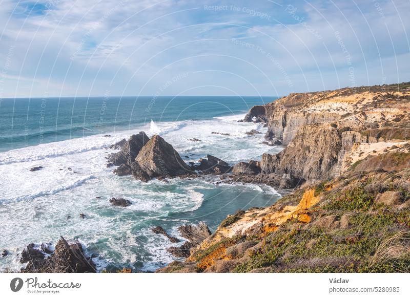 Typische Szenerie an der Atlantikküste. Hohe felsige Klippen mit Sandstränden in der Region Odemira, Westportugal. Wanderung auf dem Fischerpfad, Rota Vicentina