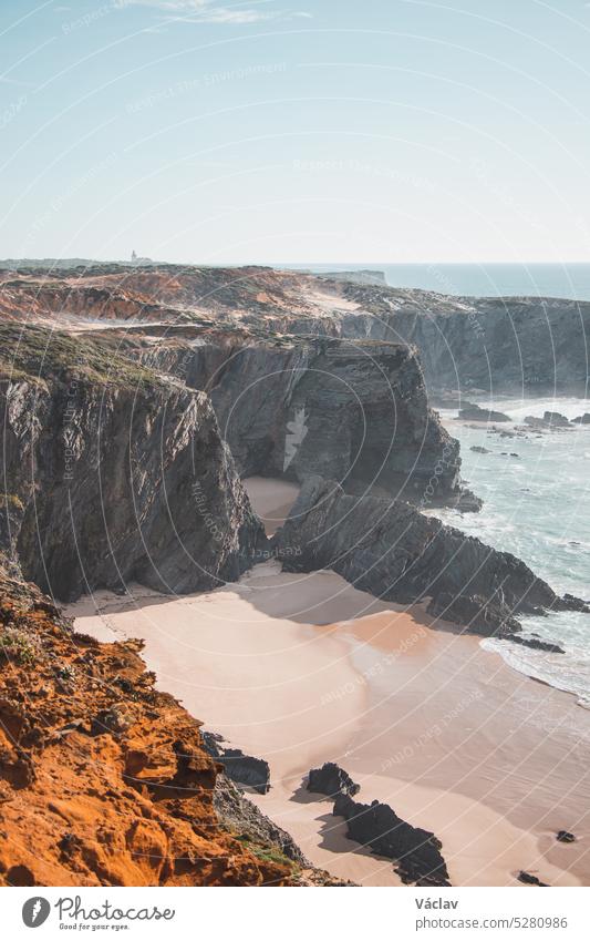 Typische Szenerie an der Atlantikküste. Hohe felsige Klippen mit Sandstränden in der Region Odemira, Westportugal. Wanderung auf dem Fischerpfad, Rota Vicentina