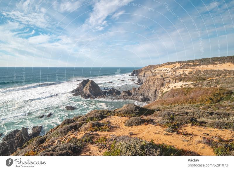 Typische Szenerie an der Atlantikküste. Hohe felsige Klippen mit Sandstränden in der Region Odemira, Westportugal. Wanderung auf dem Fischerpfad, Rota Vicentina