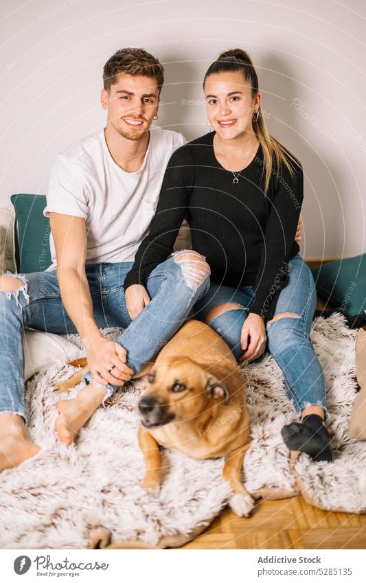 Glückliches Paar sitzt mit Hund auf dem Boden kuscheln Umarmung Plaid Haustier Tier heimisch Liebe Bonden positiv lustig jung Eckzahn heimwärts Partner Besitzer