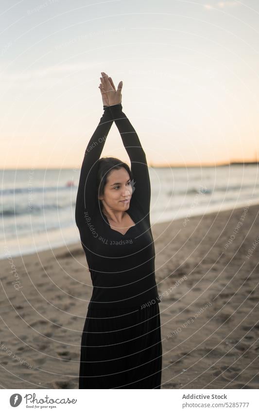 Zufriedene junge hispanische Frau tanzt am Sandstrand Tanzen Strand Sonnenuntergang Arme hochgezogen positiv MEER ausführen selbstbewusst feminin sorgenfrei