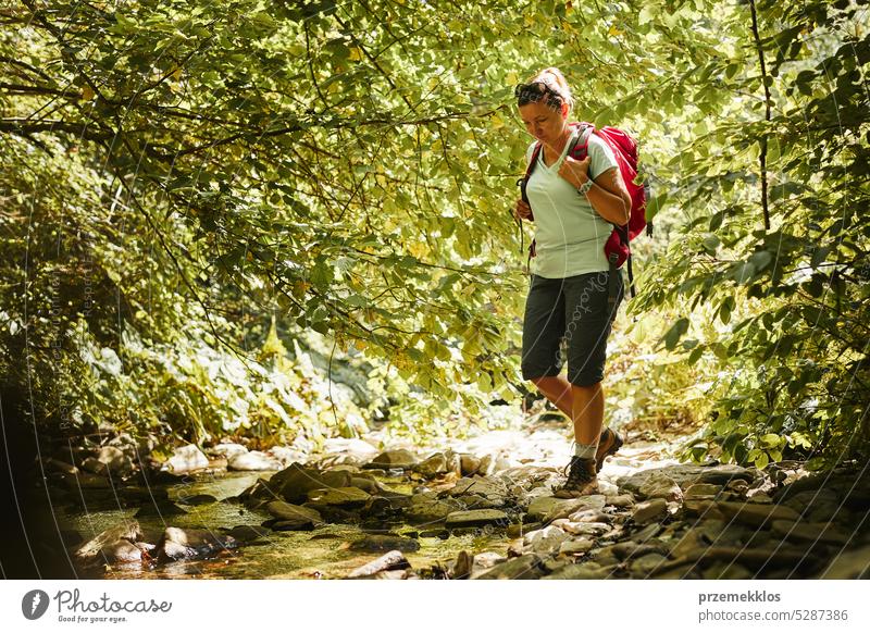 Reisen mit Rucksack Konzeptbild. Backpacker weiblich in Trekking-Stiefel überqueren Berg Fluss. Sommerurlaub Reise Abenteuer reisen Ausflug Urlaub