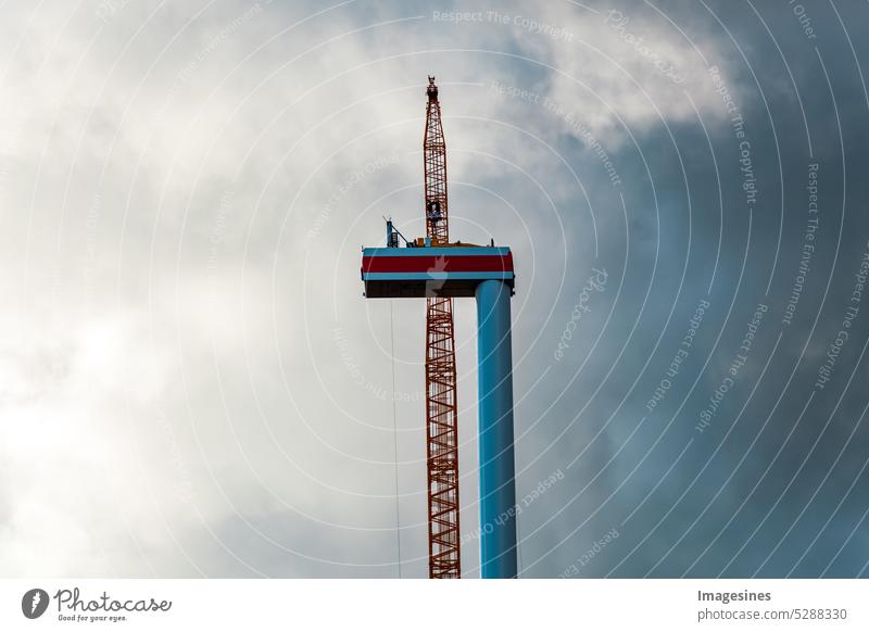 Unwetter. Bau und Montage einer Windkraftanlage per Kran und dunkle Wolken ziehen auf, Ackerland mit Bauarbeiten für Windkraftanlagen im Windpark. Gewitterwolken ziehen auf. Wörrstadt, Deutschland.