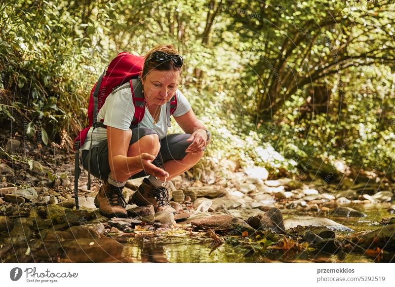 Reisen mit Rucksack Konzeptbild. Backpacker weiblich in Trekking-Stiefel überqueren Berg Fluss. Sommerurlaub Reise Abenteuer reisen Ausflug Urlaub