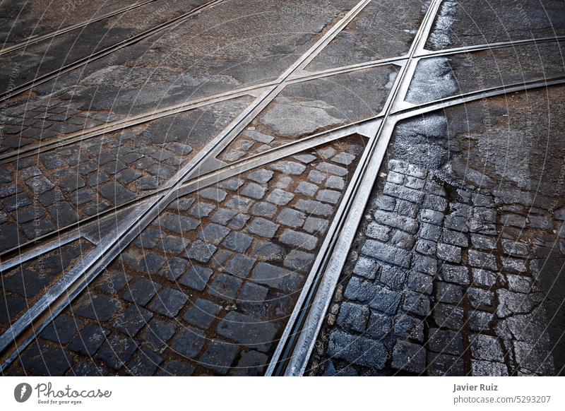 Straßenbahnübergang auf einer Kopfsteinpflasterstraße in Lissabon Portugal, mit einigen Regenpfützen, Gleiskreuzung, städtische Texturen Eisenbahn Überfahrt