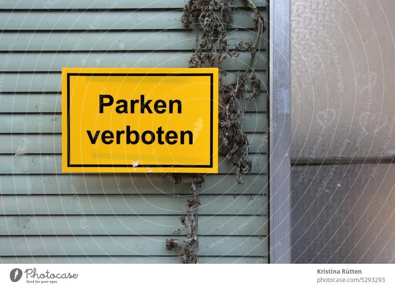 parken verboten vor dem verlassenen geschäft parkverbot schild fenster jalousie lamellen pflanzen unkraut leer natur herzen herzchen parkplatz info hinweis