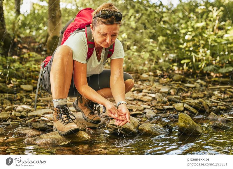 Reisen mit Rucksack Konzeptbild. Backpacker weiblich in Trekking-Stiefel überqueren Berg Fluss. Sommerurlaub Reise Abenteuer reisen Ausflug Urlaub