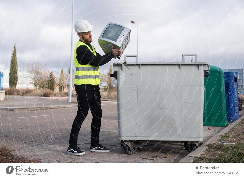 Ein Arbeiter in einer Recyclinganlage wirft einen alten Fernseher in eine Mülltonne. Technologie-Recycling-Konzept. wiederverwerten wiederverwertet recycelbar