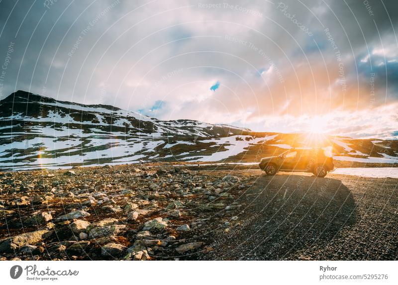 Aurlandsfjellet, Norwegen. Auto SUV geparkt in der Nähe Aurlandsfjellet Scenic Route Straße im Sommer norwegischen Landschaft. Beliebtes Reiseziel in Sonnenuntergang Lichter. Sonnenschein