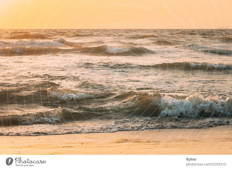 Meer Ozean Wasseroberfläche mit schäumenden kleinen Wellen bei Sonnenuntergang. Abend Sonnenlicht Sonne über Meer. Ozean Wasser Schaum spritzt Waschen Sandstrand. Crashing Wellen der sandigen Küste. Natürliche Sonnenuntergang Himmel warmen Farben. Amazing Landschaft Landschaft. Kopieren Raum. Nat...