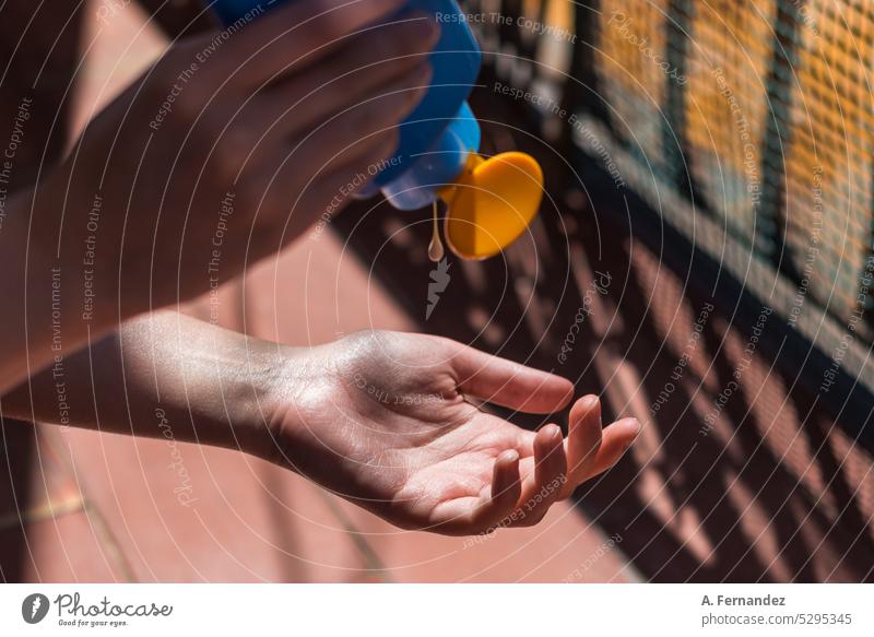 Frau mit einer Flasche Sonnenschutzmittel in der Hand, die sie an einem sonnigen Sommertag auf ihre Handfläche aufträgt. Sonnencreme Sahne Feiertag Pflege