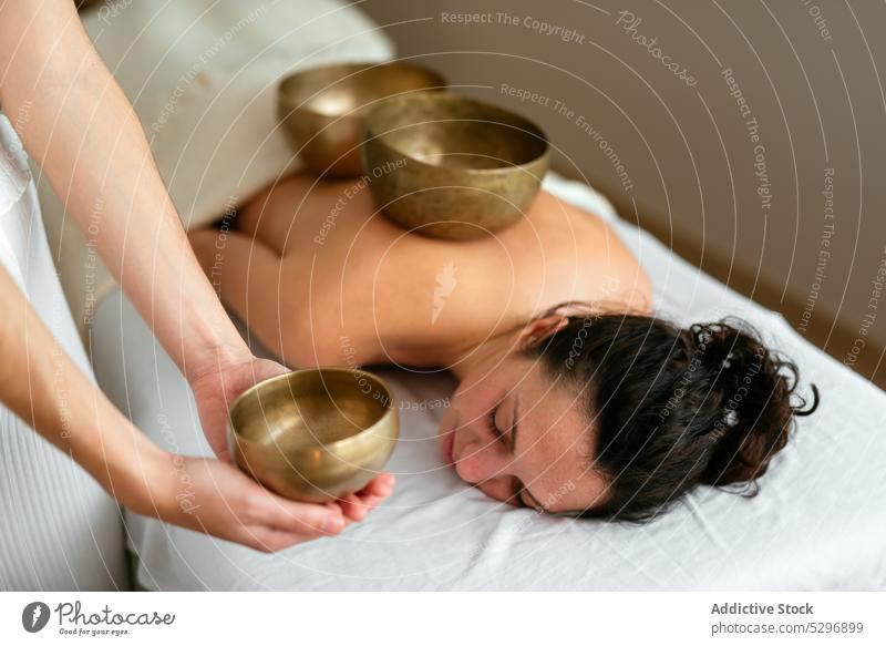 Frau auf der Couch liegend mit geschlossenen Augen während einer Meditationssitzung mit Klangschale Frauen meditieren Therapeut Massage Wiederherstellung Spa