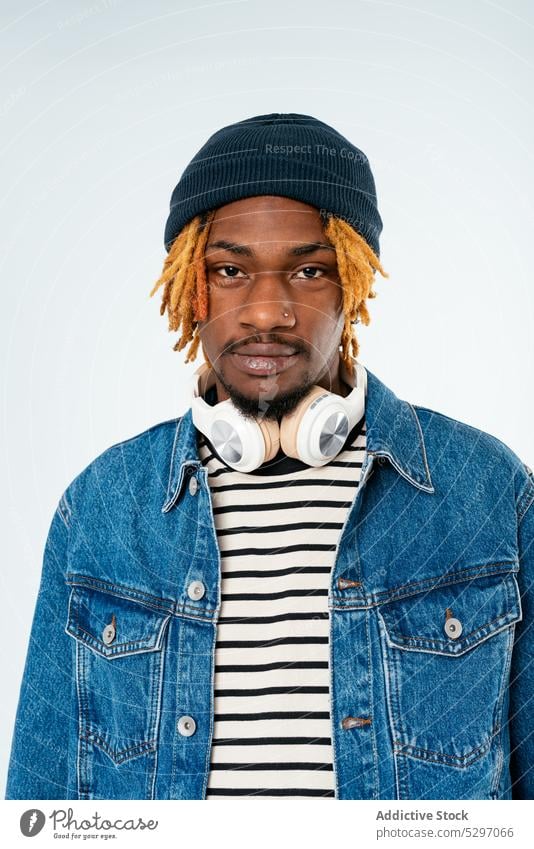 Stylischer schwarzer Mann mit Dreadlocks in Jeansjacke Stil Jeansstoff Outfit Lächeln Rastalocken Streetstyle cool Studioaufnahme Atelier selbstbewusst