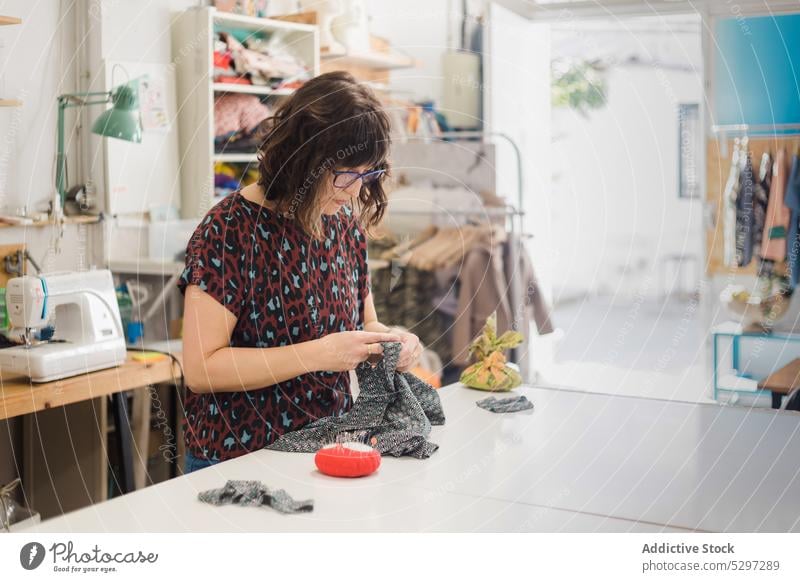 Konzentrierte Frau beim Nähen von Kleidung in einer Werkstatt Näherin Damenschneiderin Muster nähen Atelier Textil Gewebe Stoff Designer Konzentration Fokus