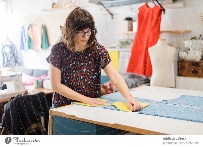 Konzentrierte Frau, die im Atelier ein Muster zum Nähen vorbereitet Näherin Designer Gewebe Damenschneiderin Stoff Werkstatt Textil Schneider kreativ Material