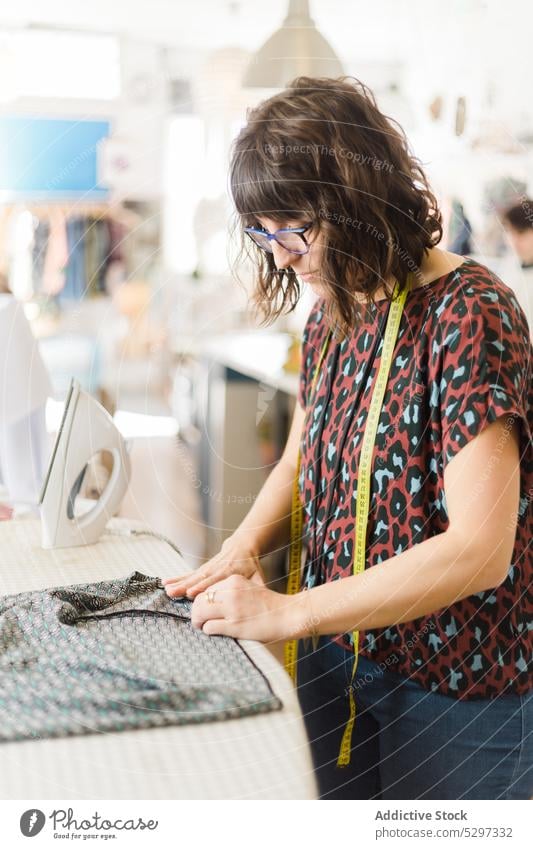 Frau bügelt Stoff im Atelier Damenschneiderin Klebeband messen bügeln Schneider Werkstatt professionell Arbeit Textil Gewebe Prozess Näherin Designer Job nähen