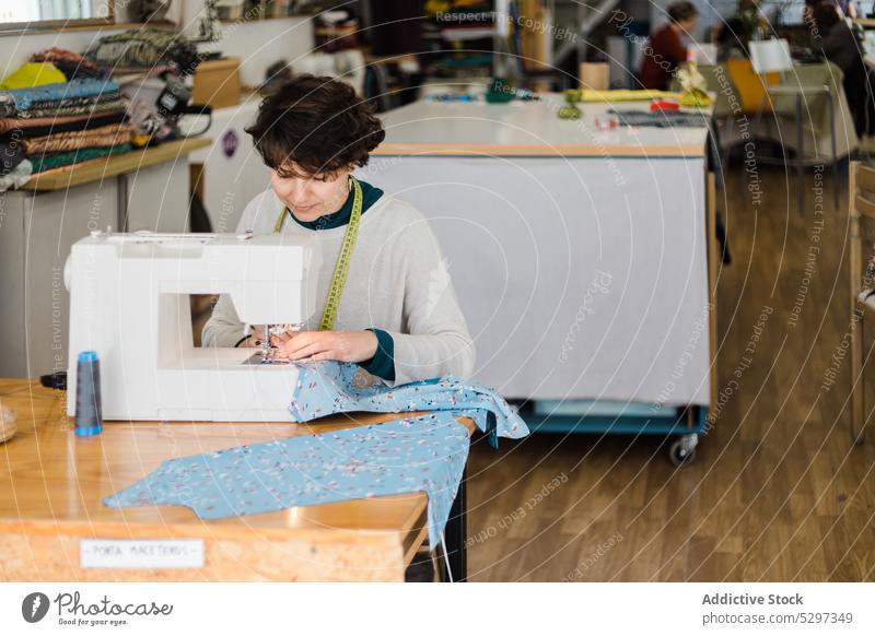 Gezieltes Schneidern an der Maschine im Atelier Frau Näherin Damenschneiderin Klebeband Designer Werkstatt messen Nähmaschine Muster Arbeit professionell