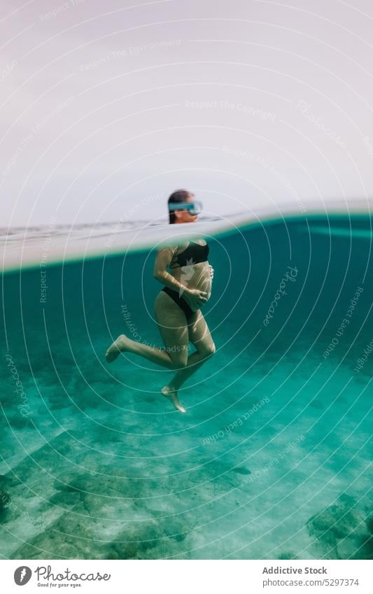 Unerkennbare schwangere Frau beim Tauchen im Meer schwimmen unter Wasser Fisch Sinkflug unterseeisch Urlaub MEER Bikini durchsichtig blau Feiertag reffen