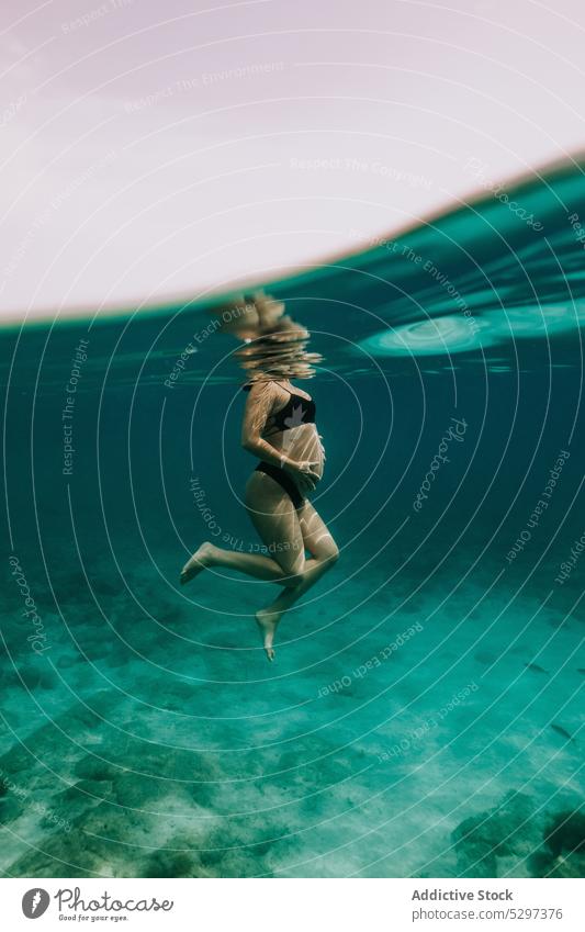 Unerkennbare schwangere Frau beim Tauchen im Meer schwimmen unter Wasser Fisch Sinkflug unterseeisch Urlaub MEER Bikini durchsichtig blau Feiertag reffen