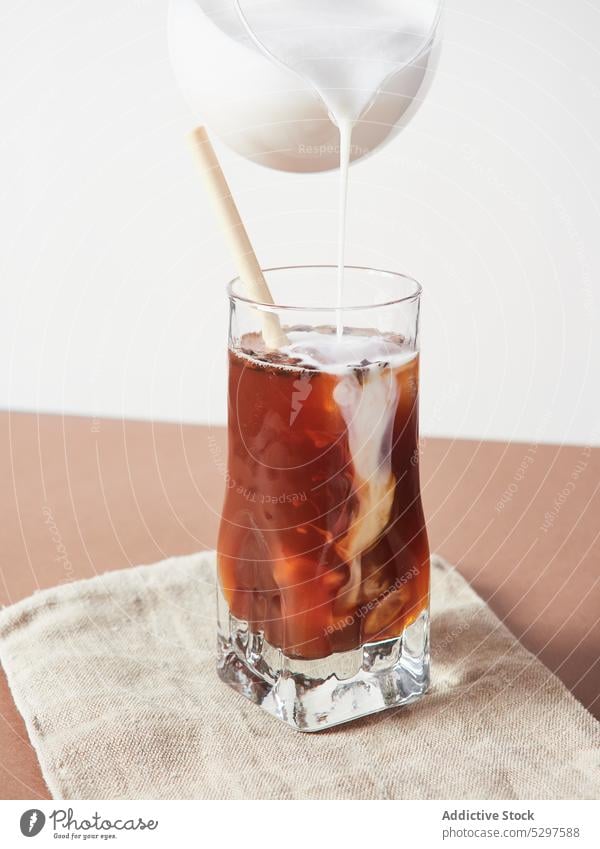 Eine Person gießt Milch in ein Glas Kaffee gepeitscht Sahne melken hinzufügen trinken süß eingießen vorbereiten lecker geschmackvoll Getränk frisch Milchshake