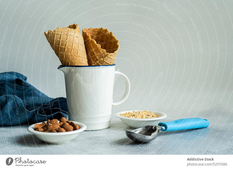 Waffeltüten und Nüsse für die Zubereitung von Speiseeis Zapfen Mandel gehackt kalt Beton Koch Essen zubereiten Tasse Delikatesse Dessert essen Lebensmittel