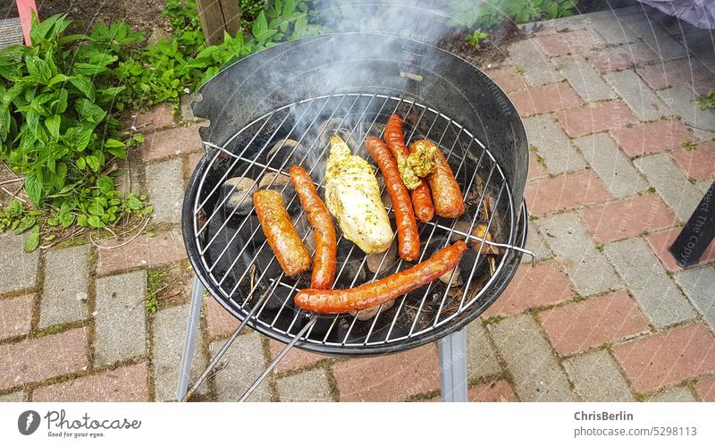 Holzkohlengrill mit Würstchen holzkohlegrill Grill Grillrost Grillsaison Fleisch Ernährung Lebensmittel Grillwürste Außenaufnahme lecker heiß Farbfoto