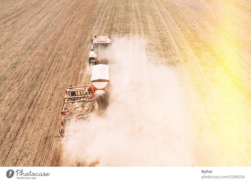 Erhöhte Ansicht Traktor mit Sämaschine Aussaat von Saatgut für Pflanzen im Frühjahr. Beginn der landwirtschaftlichen Frühjahrssaison. Countryside Rural Field Landschaft. Sonnenlicht Sonnenstrahl Sonnenschein