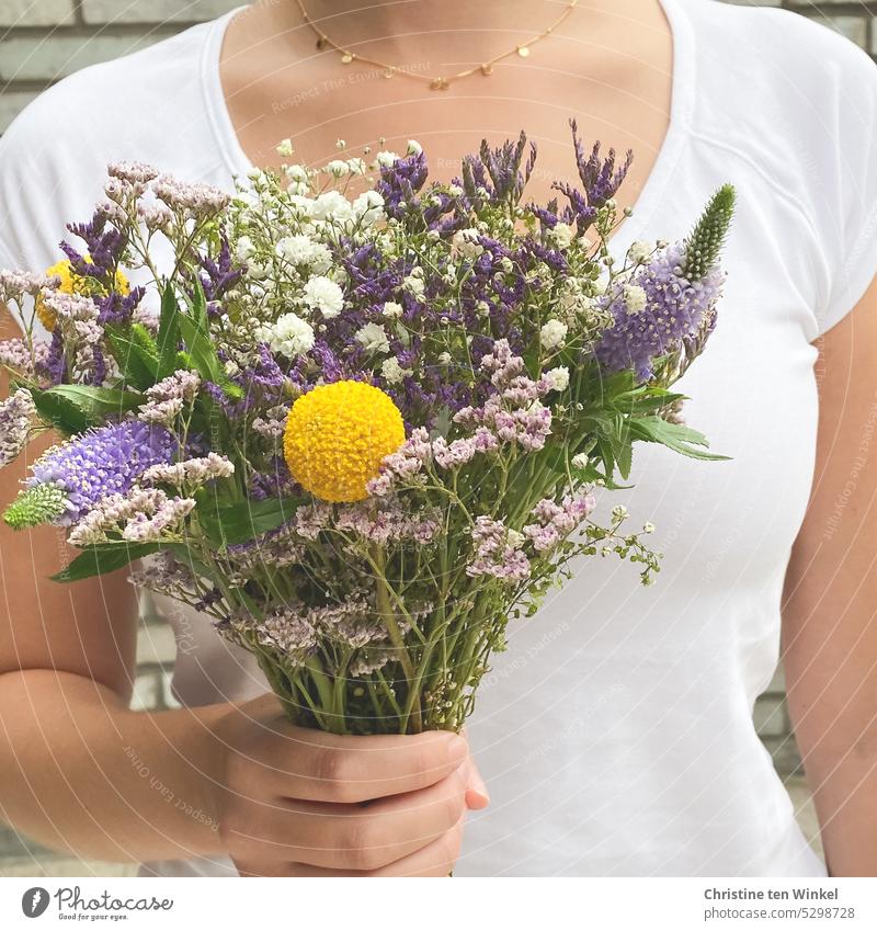 Eine junge Frau hält einen bunten Blumenstrauß in der Hand Geschenk Muttertag Valentinstag Geburtstag Liebe Schnittblumen Freude schön posieren festhalten