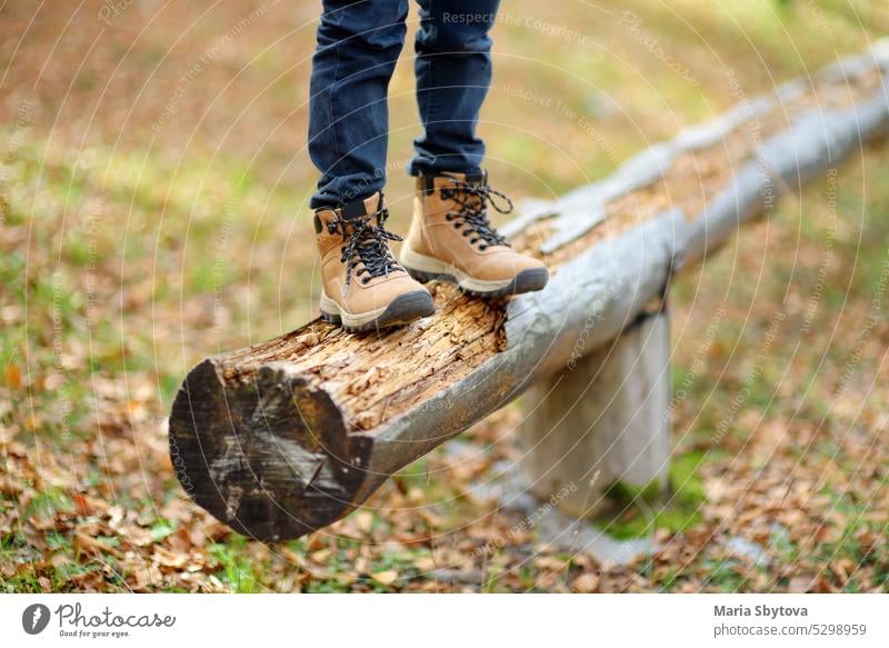 Fröhliches Kind beim Spaziergang im Wald an einem sonnigen Herbsttag. Preteen Junge hat Spaß beim Spaziergang durch den Herbst Wald. Wanderung Bein Stiefel Fuß