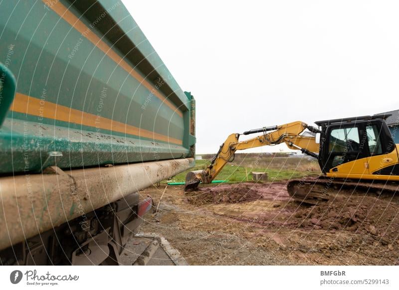 Auf der Baustelle - Erdarbeiten zur Vorbereitung eines Baugrundstücks für den Hausbau mit Bagger und LKW Bager Lkw Lastwagen baggern Baumaschinen Arbeiten