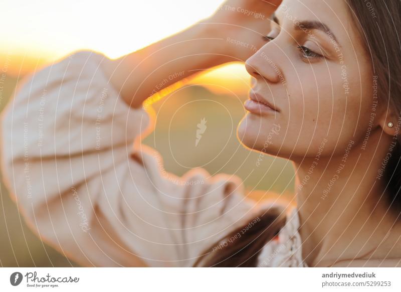 schöne junge frau mit langen haaren und strohsack in der hand im sommer bei sonnenuntergang im feld spazieren. sie ist glücklich. hintergrund unscharf kunstfotografie. sommerurlaub konzept.