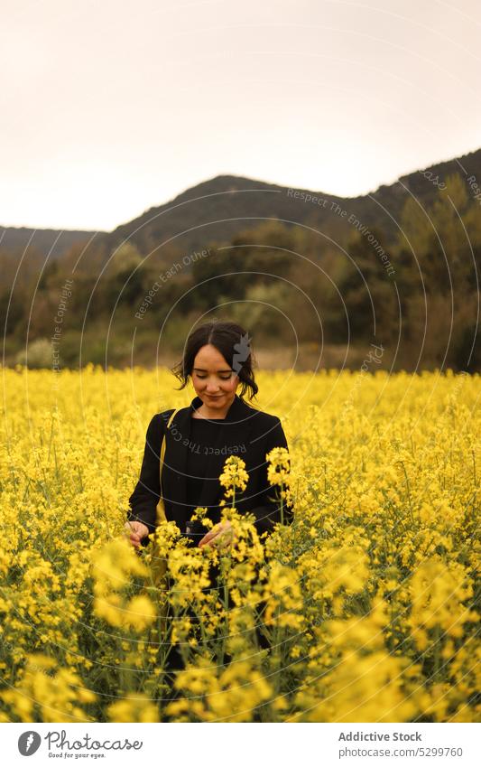 Zufriedene Frau im blühenden Feld Blume Landschaft Wiese Windstille Natur Blütezeit Hügel Umwelt friedlich Flora ruhig jung Gelassenheit Harmonie ländlich