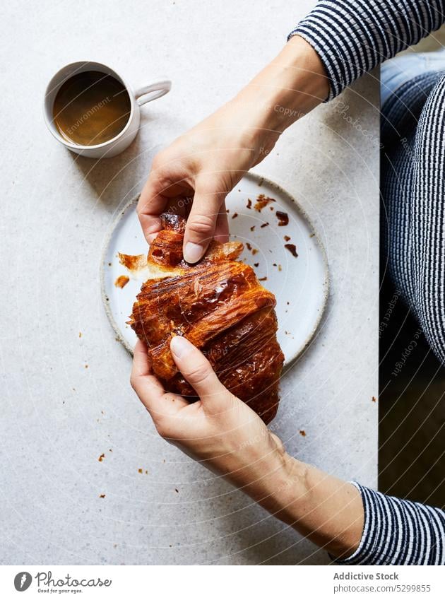 Gesichtslose Person isst leckeres Croissant Frühstück gebacken essen Kaffee Lebensmittel selbstgemacht Tisch Morgen Gebäck Dessert Teller geschmackvoll Tasse