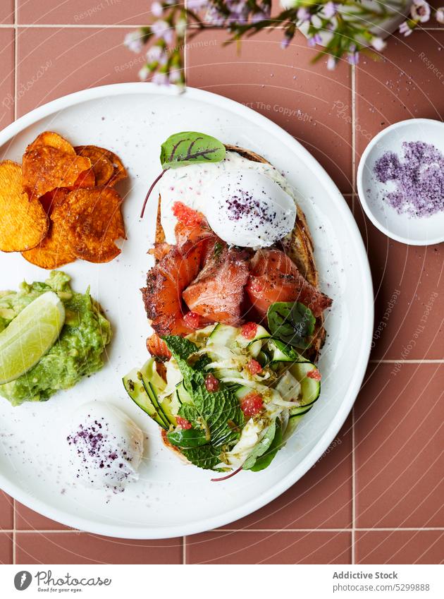 Leckerer Toast mit Lachs und pochiertem Ei Zuprosten Avocado Salatgurke Mahlzeit Lebensmittel Frühstück lecker Teller Speise geschmackvoll Gastronomie