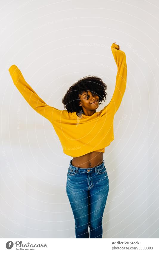 Positive schwarze Frau in lässigem Outfit auf weißem Hintergrund Bauch Vorschein positiv Afro-Look Inhalt heiter Lächeln Glück Frisur Afroamerikaner jung