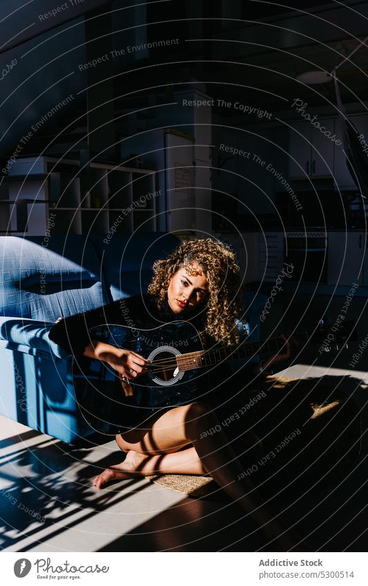 Konzentrierte Frau spielt Gitarre auf dem Boden spielen Musik Musiker Instrument Gitarrenspieler üben Fenster Hobby akustisch jung Melodie Talent Klang