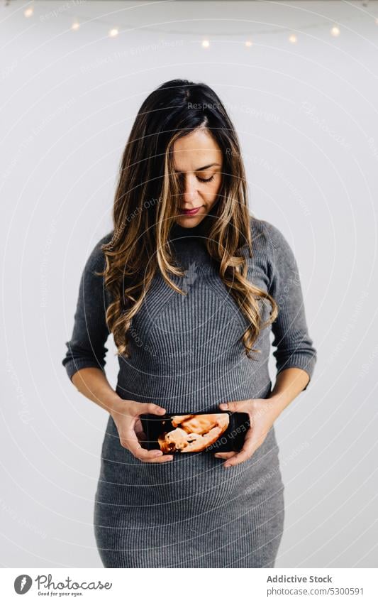 Junge schwangere Frau mit Fötus Foto Bauch Smartphone Girlande glühen warten erwarten Windstille Stil Kleid pränatal Gerät Apparatur Drahtlos Anschluss