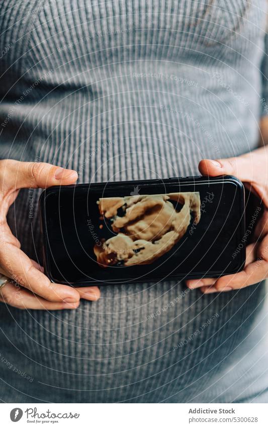 Anonyme schwangere Frau mit Fötus Foto Bauch Smartphone Girlande glühen warten erwarten Windstille Stil Kleid pränatal Gerät Apparatur Drahtlos Anschluss