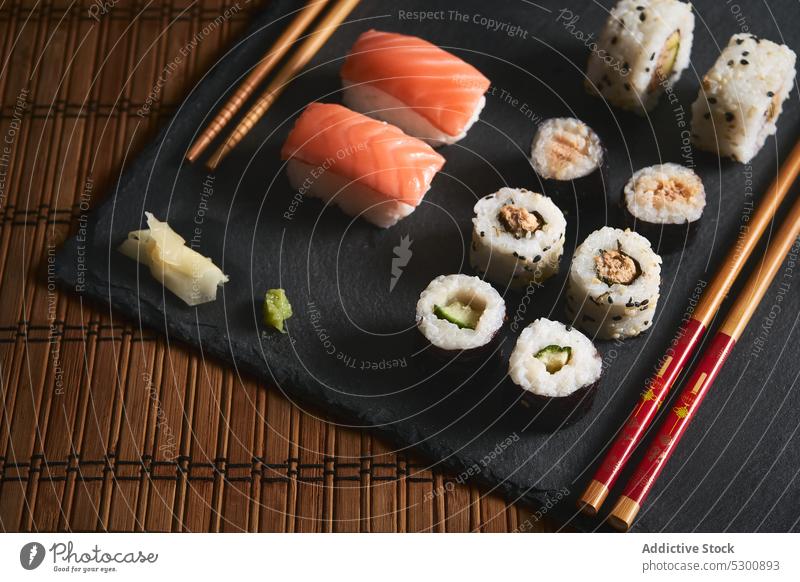 Leckere Sushi-Rollen mit Stäbchen an Bord rollen Japanisch Holzplatte Wasabi Meeresfrüchte Fisch Küche Ingwer Essstäbchen Lebensmittel Asiatische Küche Mahlzeit